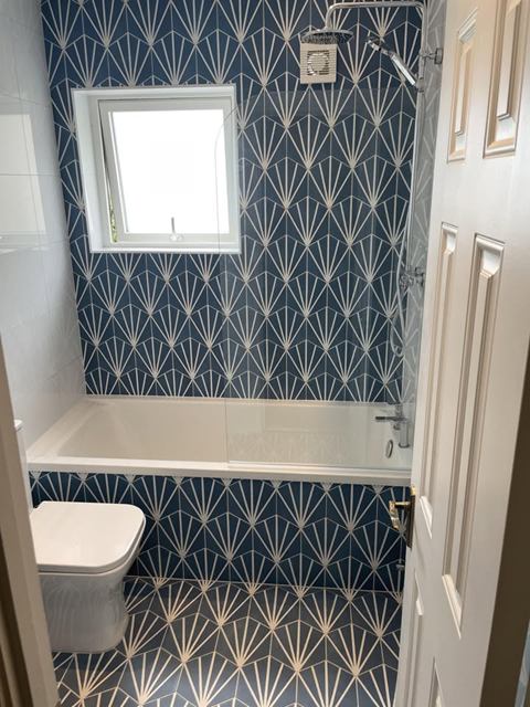 Bathroom tiled floor to ceiling in blue and white fan-pattern tiles around a bath
