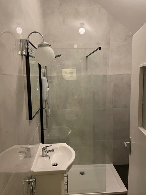 Walk-in shower with a frameless glass screen and large concrete-effect wall tiles