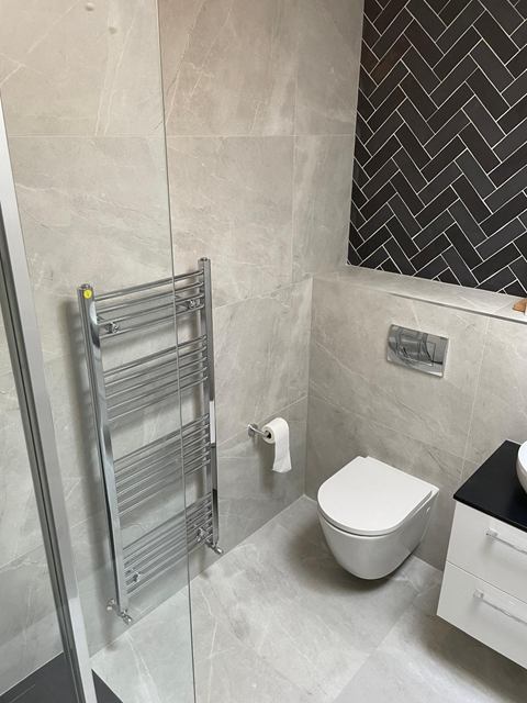 Grey stone-effect tiles with a black herringbone feature wall and wall-hung toilet