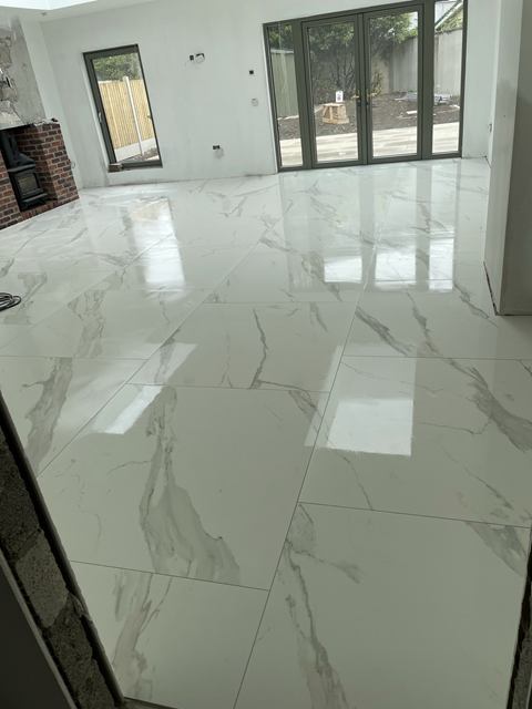 Large-format gloss marble-effect floor tiles across an open-plan extension