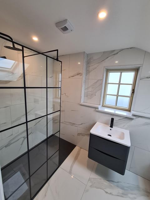 Walk-in shower with a black framed glass screen, marble-effect tiles and a floating vanity